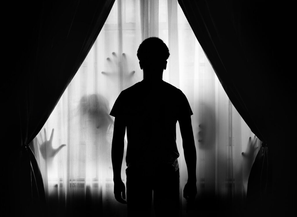 Frightening silhouette of man with human shapes behind him